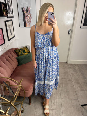 Light and airy long flowing floral print dress with a bardot collar on the front. Adjustable straps, sleeveless with bare shoulders. Elastic seam at waist and back. Square bare back. Fitted cut. Gathered seam on the skirt for more fullness. Lace detail at the base and flared.