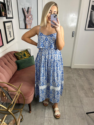 Light and airy long flowing floral print dress with a bardot collar on the front. Adjustable straps, sleeveless with bare shoulders. Elastic seam at waist and back. Square bare back. Fitted cut. Gathered seam on the skirt for more fullness. Lace detail at the base and flared.