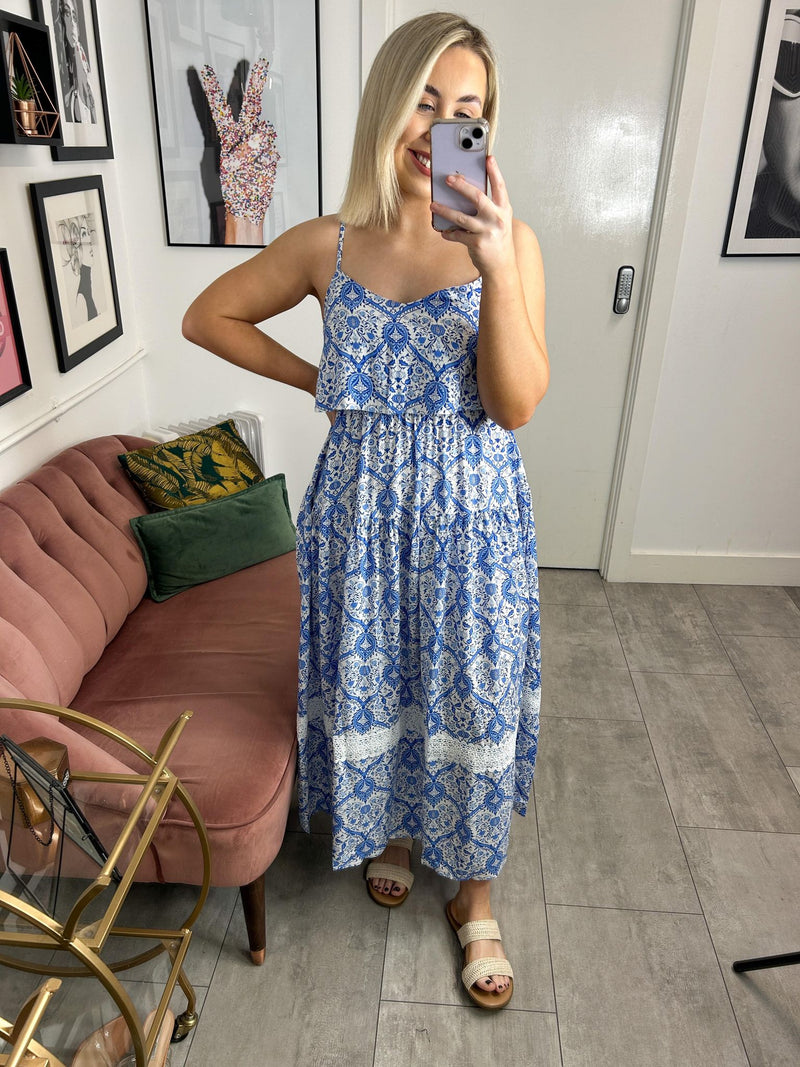 Light and airy long flowing floral print dress with a bardot collar on the front. Adjustable straps, sleeveless with bare shoulders. Elastic seam at waist and back. Square bare back. Fitted cut. Gathered seam on the skirt for more fullness. Lace detail at the base and flared.