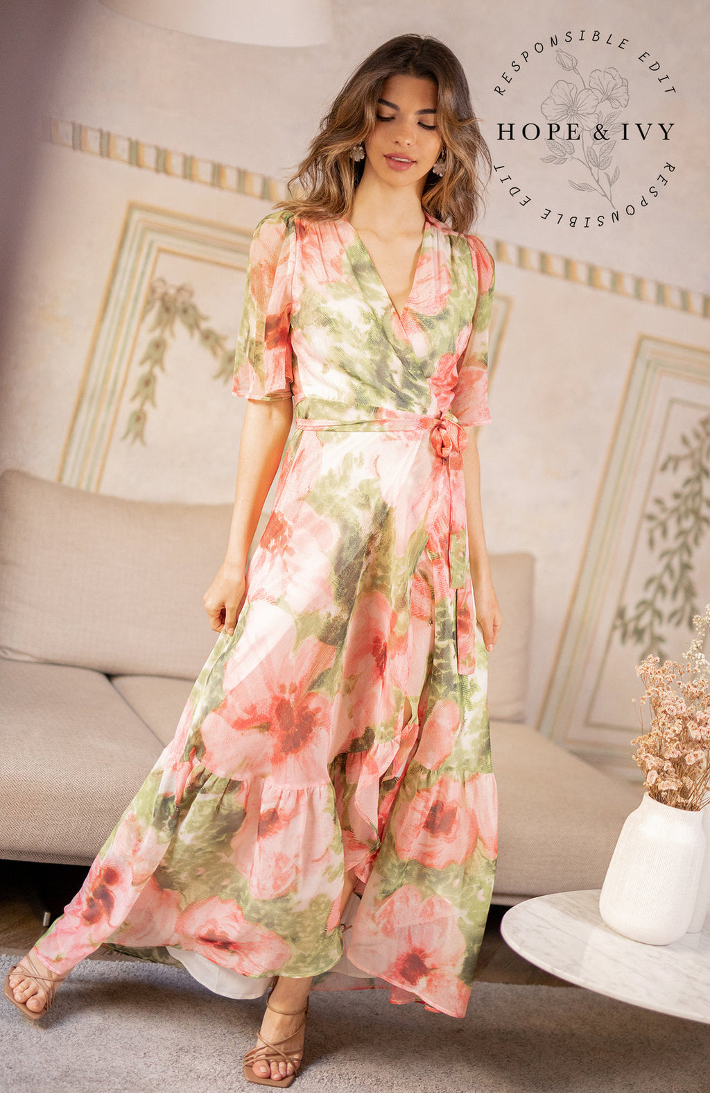 The hand-design print depicts romantic brushed petals in muted florals scattered on a soft base. Full flutter sleeves and a tie waist feature complete the wrap front bodice with a drop hem skirt that finishes at floor length. Whatever this Spring has in hold for you, glide with grace in this celestial dress.
