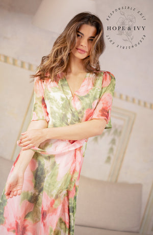 The hand-design print depicts romantic brushed petals in muted florals scattered on a soft base. Full flutter sleeves and a tie waist feature complete the wrap front bodice with a drop hem skirt that finishes at floor length. Whatever this Spring has in hold for you, glide with grace in this celestial dress.