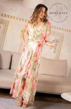 The hand-design print depicts romantic brushed petals in muted florals scattered on a soft base. Full flutter sleeves and a tie waist feature complete the wrap front bodice with a drop hem skirt that finishes at floor length. Whatever this Spring has in hold for you, glide with grace in this celestial dress.