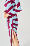 Midi dress with adjustable side gathering and shoulder pads. Long sleeves and round neck. Side vent. Back fastening with button.