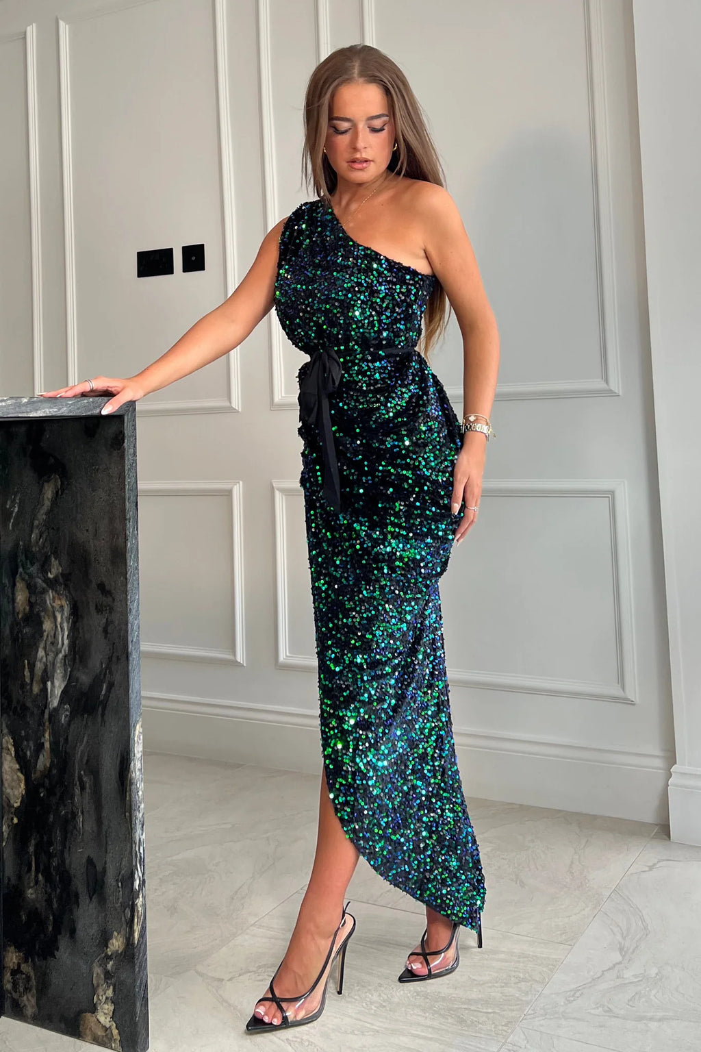 Featuring a wrap over skirt with ruched sides, one shoulder detail and a belt to cinch in the waist, all in this gorgeous velvet sequin. Style with some elegant heels and accessories for this chic look.
