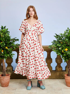 Midi dress in a drapey heart print fabric. Featuring a sweetheart neckline, finished with embroidered ruffle edges. Decorative gem button complete the look.