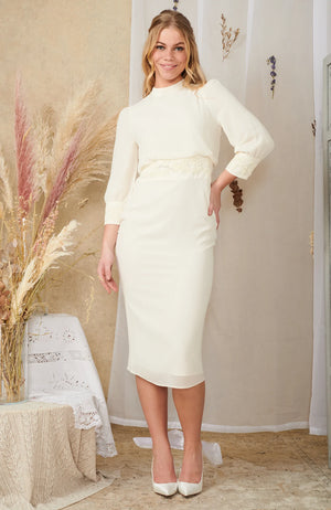 This flattering, body hugging midi dress is perfect for the chic bride on her wedding day. Featuring embellishment across the waistline and sleeves, high neck and open back detail, this silhouette is sure to become a quick classic.