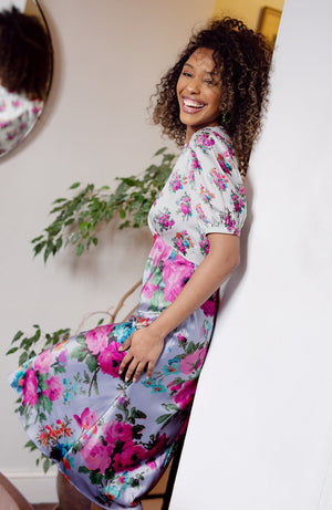 Contrasting panels of hand-designed stylised florals bloom across lilac and white satin bases, in power pinks and oranges. With a puff blouson sleeve, tie back detail and high cut neckline, this gorgeous silhouette is sure to inspire and enchant onlookers whatever the event this season.