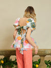 Sister Jane DREAM Primula Postcard Scallop Top. Open back top in a bright floral organza jacquard fabric. Featuring a scallop edge neckline and hem with short puff sleeves. Adjustable ties bow at the back. Fully lined in a soft touch fabric