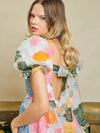 Sister Jane DREAM Primula Postcard Scallop Top. Open back top in a bright floral organza jacquard fabric. Featuring a scallop edge neckline and hem with short puff sleeves. Adjustable ties bow at the back. Fully lined in a soft touch fabric