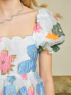 Sister Jane DREAM Primula Postcard Scallop Top. Open back top in a bright floral organza jacquard fabric. Featuring a scallop edge neckline and hem with short puff sleeves. Adjustable ties bow at the back. Fully lined in a soft touch fabric